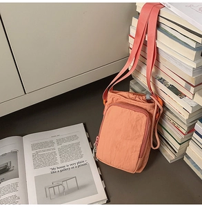 Detail of water-resistant nylon shoulder bag in orange pink with adjustable strap