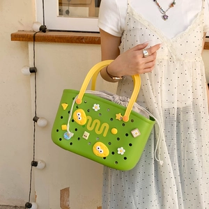 Detail of green EVA hollow tote bag with yellow handles and cartoon charms decoration