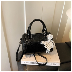 Détail du sac boston en cuir verni noir brillant avec breloque cœur en perles et dentelle