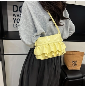 Close-up of stylish pale yellow crossbody bag with layered ruffle details and crossbody strap