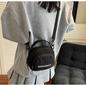 Detail of black nylon crossbody bag with double zippers and adjustable shoulder strap