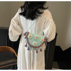 Detailed close-up of light blue crochet bucket bag with pink floral accents and tassels