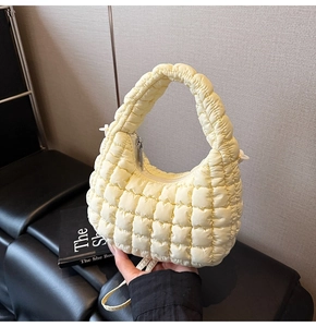 Detail of light yellow quilted cloud bag showing soft fabric texture and zipper