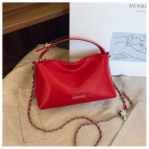 Detail of red leather shoulder bag with silver chain strap and metal logo plaque