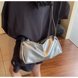 Detailsicht der silbernen Metallic-Kissentasche mit Fashion-Schriftzug und feinem Gurt