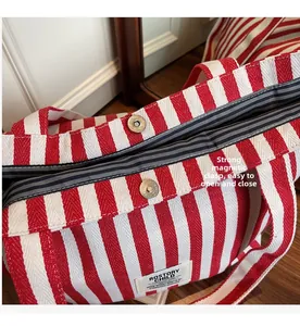 Detail of red and white striped canvas tote bag showing secure dual magnetic snap closures