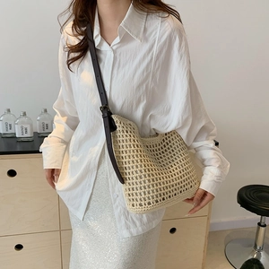 Detail of off-white woven mesh shoulder bag with adjustable brown leather strap on model