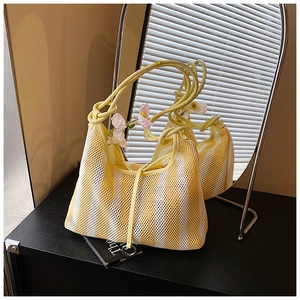 Detail of yellow and white striped mesh tote bag with knotted handles and metallic decor