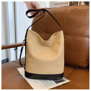 Close-up of woven bucket bag with black leather base and silver metal buckle details