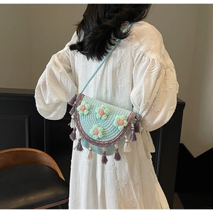 Detail of hand-woven bohemian bucket bag with crochet flowers and hanging tassels