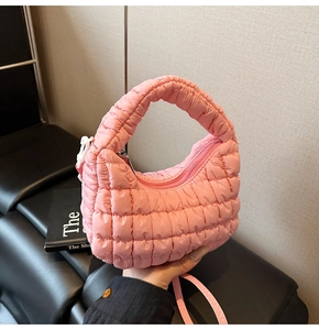 Close-up of pink quilted puffer handbag featuring soft nylon fabric and crescent shape
