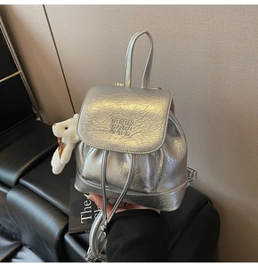 Detail of silver metallic bucket backpack with pleated texture and plush bunny charm