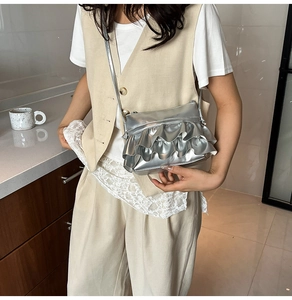 Close-up of stylish silver pleated shoulder bag with metallic ruffle detail finish