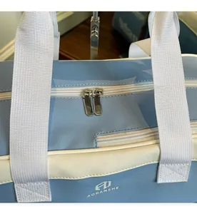 Detail of smooth double zippers and white woven handles on blue travel bag