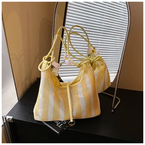 Detail of yellow and white striped mesh tote bag with rope handles on a black table