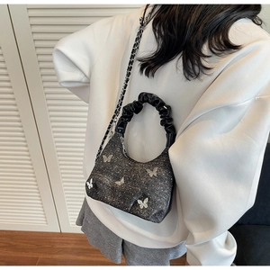 Detail of dark grey sequin handbag with silver butterfly accents and chain strap