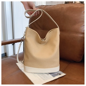 Close-up of beige woven bucket bag with white leather base and metal hardware detail