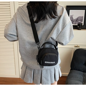 Detail of black nylon crossbody bag with adjustable strap and brand logo shown on model