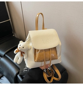 Detail of white glossy leather mini backpack with yellow handle and plush bear charm