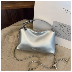 Close-up of silver tote bag showing metallic chain strap and branded metal logo plate