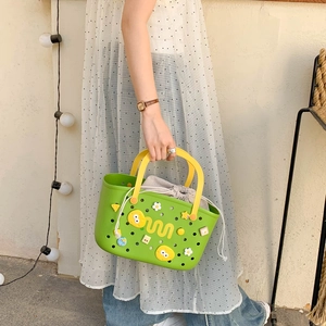 Detail of green EVA bath basket featuring cartoon charms and a yellow handle with inner bag