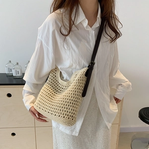 Detail of hand-woven beige tote with dark brown leather strap and adjustable metal buckle