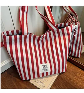 Detail view of red and white striped canvas tote bag on dark wood floor in casual setting