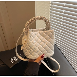 Dettaglio di una borsa a secchiello bianca con trapuntatura a rombi e strass brillanti