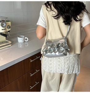 Detailed view of metallic silver ruffle shoulder bag with pleated ruffles on the back
