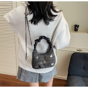 Close-up of sequined grey handbag with silver butterfly patch and pleated handle