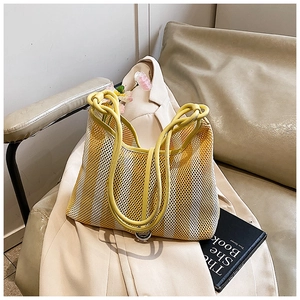 Detailed close-up of yellow and white striped knitted mesh bag on a beige blazer