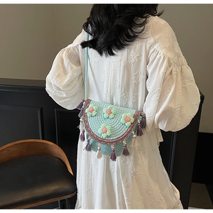 Detail showing handmade crochet flowers and tassels on light blue woven bucket bag