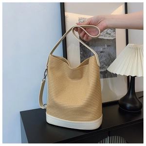 Close-up of beige woven bucket bag with white leather trim on a minimalist side table