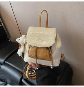 Detail of cream and camel bucket backpack with crinkled texture and plush bear charm