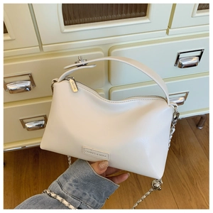 Detail of minimalist cream PU leather handbag with silver chain strap and metal logo