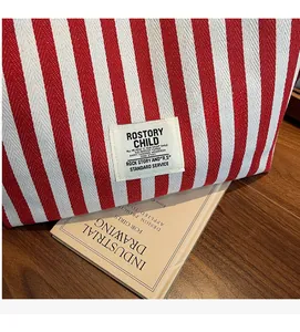 Detailed close-up of red and white striped canvas tote bag with a vintage brand label