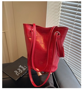 Detail of red crocodile texture tote bag with thin double straps and embossed branding
