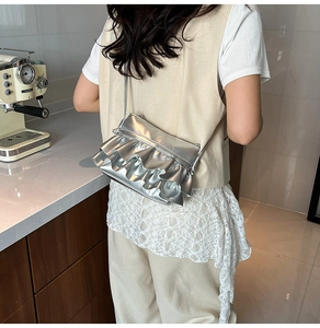 Detail showing metallic silver ruffle crossbody bag with layered tiers worn by a model