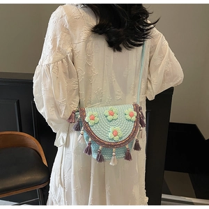 Detail of light blue hand-woven bucket bag with 3D floral accents and fringe tassels