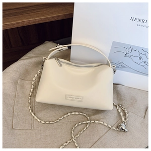 Detail of cream leather shoulder bag with chain strap and brand logo on a soft base