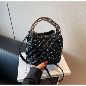Dettaglio della borsa a secchiello nera trapuntata con strass e manico a catena intrecciata