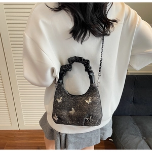 Detail of black glitter hobo bag with silver butterfly 3D accents and metal chain strap