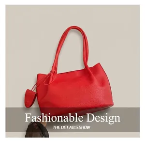 Detail of red lychee pattern leather tote bag with a matching teardrop charm on side