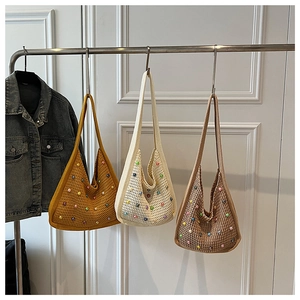 Three knit beach bags in yellow, beige and brown with colorful pearls hanging on a door