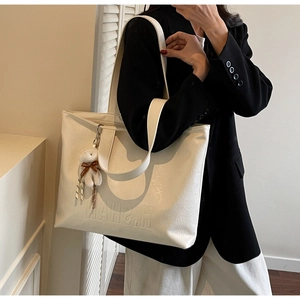 Close-up of white tote bag with embossed H.SHAN lettering and plush rabbit charm