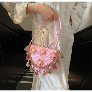 Close-up of pink woven bucket bag with 3D floral accents and colorful fringe tassels