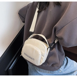 Close-up of beige canvas crossbody bag with zip pocket and adjustable shoulder strap