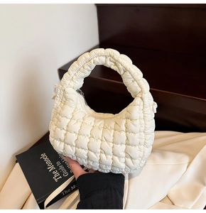 Close-up of creamy quilted cloud bag with puffy texture and integrated handle