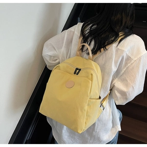 Detail view of bright yellow canvas backpack with side pocket and adjustable strap