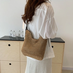 Close-up of brown hand-woven mesh tote bag with dark shoulder strap on a model